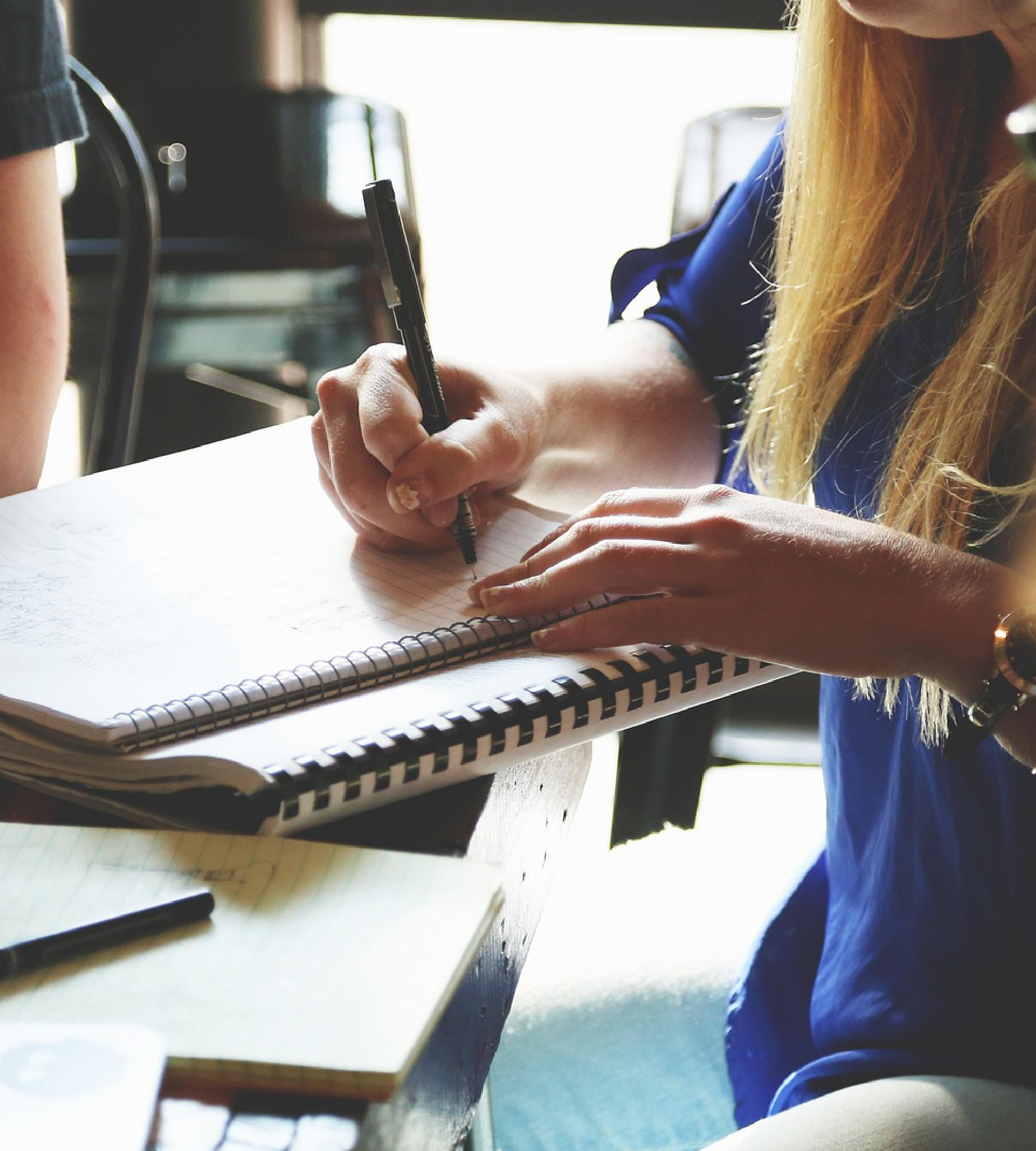 Women writing notes in a notebook in a coffee shop